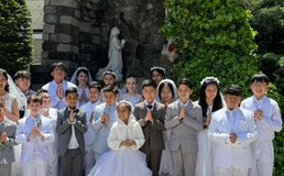 Group of children in front of Marian grotto after first communion