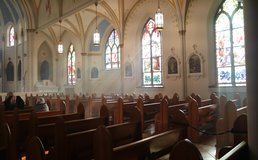 Sun shines through stained glass windows into a Catholic Church