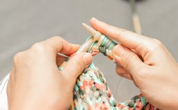 two hands knit a colorful garment