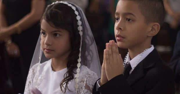 a boy and a girl stand in line for their First Holy Communion