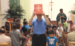 man holding bible with children from mustard seed group