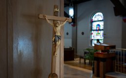 crucifix in church with stained glass window in background