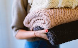 woman holds a stack of blankets