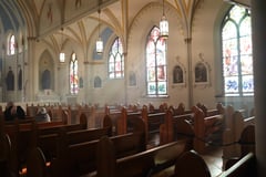 Sun shines through stained glass windows into a Catholic Church