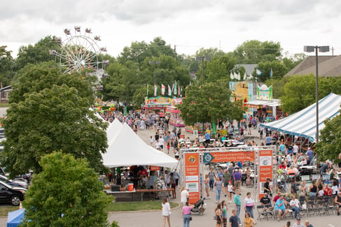 An aerial view of the Our Lady of Perpetual Help parking lot crowded with tents, rides, and festival-goers