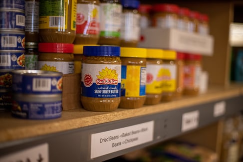 peanut butter and canned goods sit on a shelf